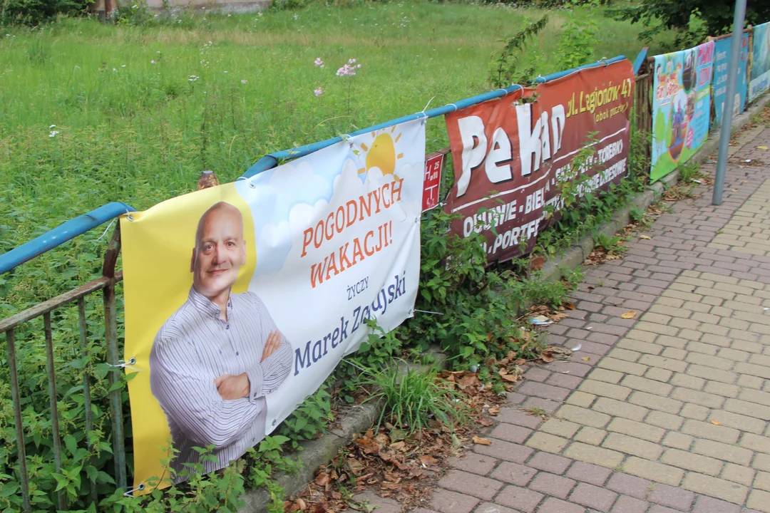 Mężczyzna  z plakatu życzy pogodnych wakacji.  Tak bezinteresownie? - Zdjęcie główne